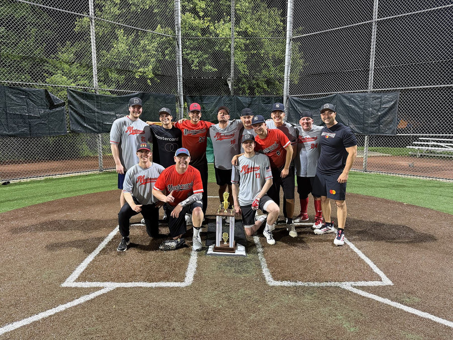 Mastercard corporate softball team in custom gray and red 7Bros jerseys posing with a league trophy at home plate