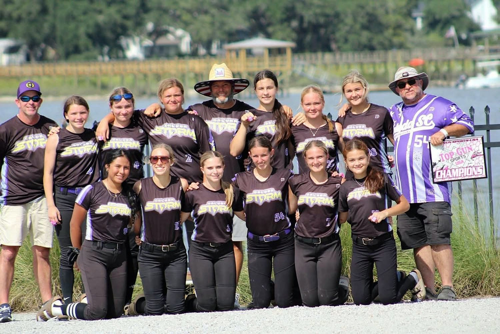 Saluda Storm softball team and coaches in custom black and purple 7Bros jerseys with a Top Gun champions plaque
