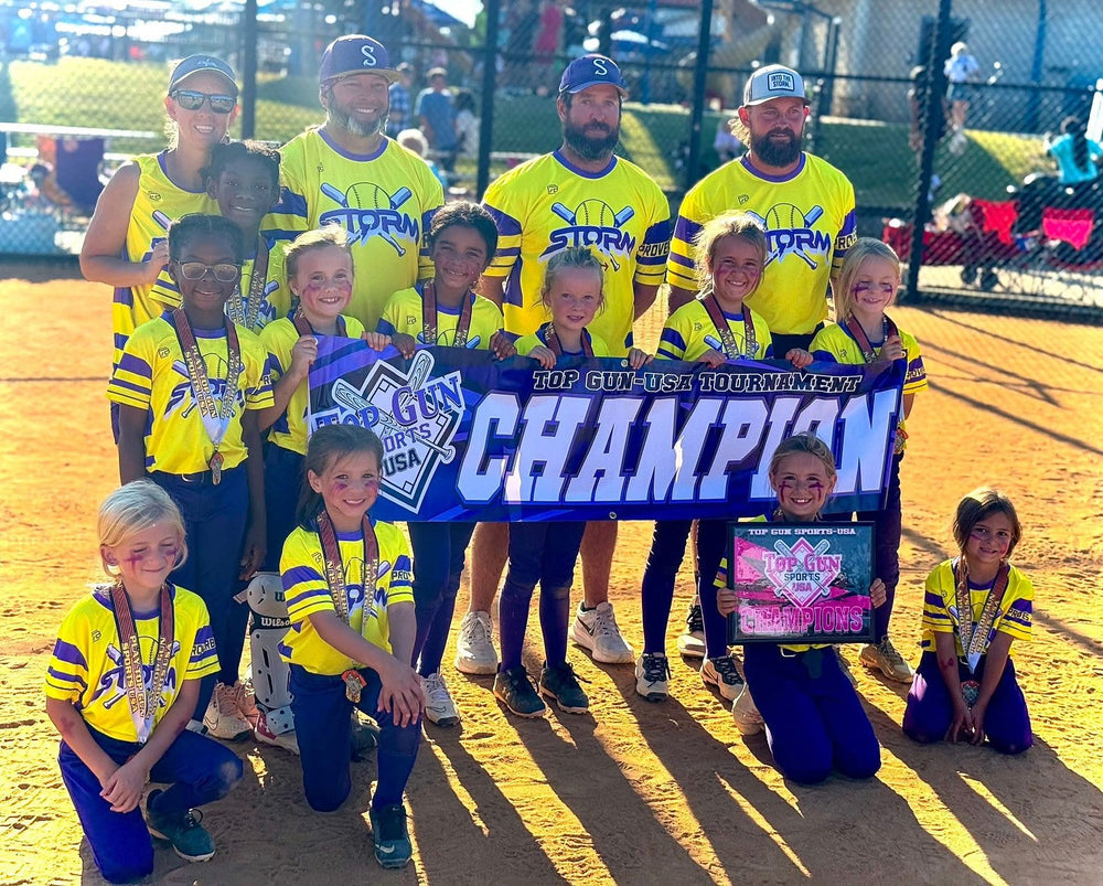 Saluda Storm 8U softball team and coaches in custom yellow and purple 7Bros jerseys holding a Top Gun USA tournament champion banner