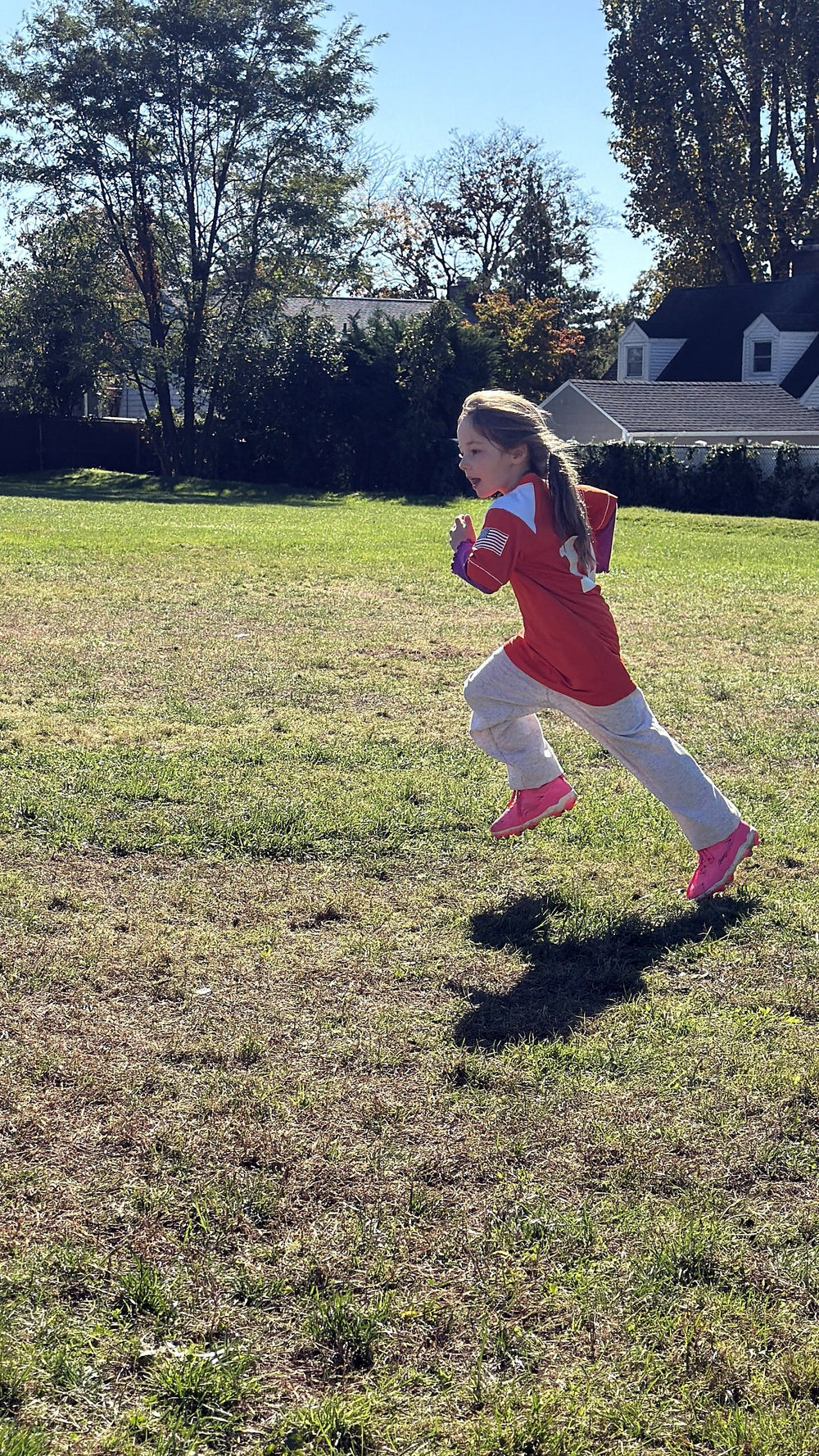 Young player sprinting across a field in a custom orange and white 7Bros flag football jersey
